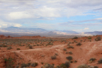 Photo of red sedimentary rock formations in the foreground and low lying mountains in the background